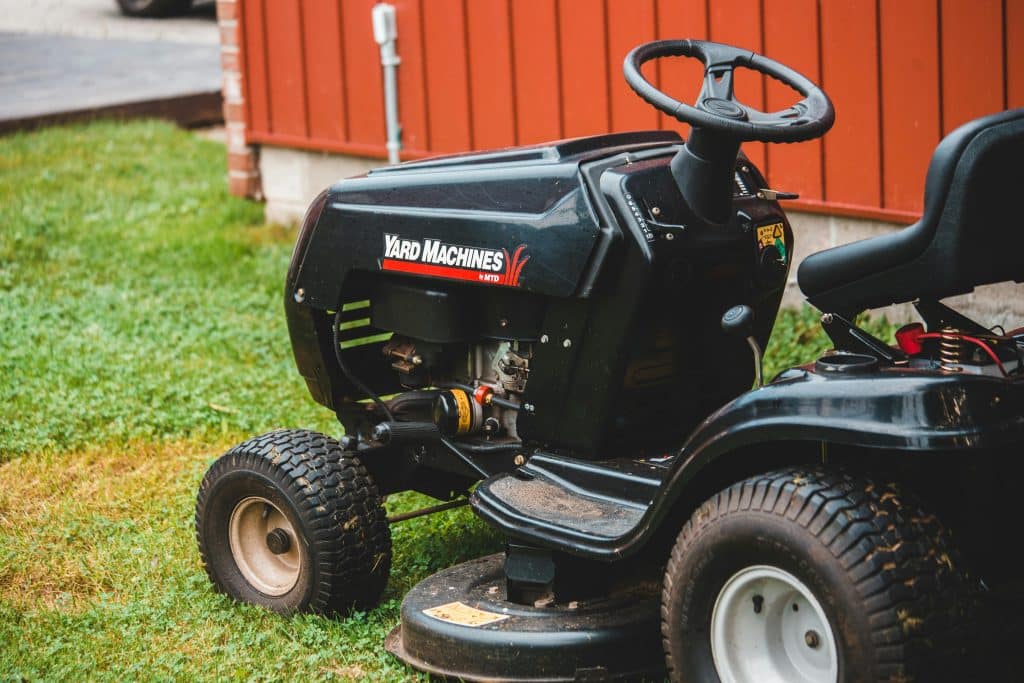 Fekete szinű munkagép látszik a képen egy fűnyíró traktor